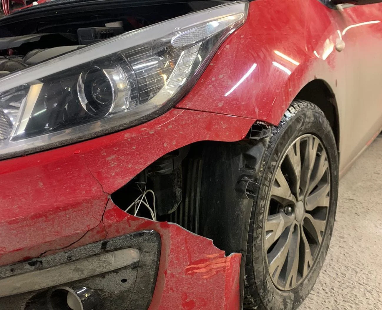 Красный Kia с поврежденным передним бампером до ремонта